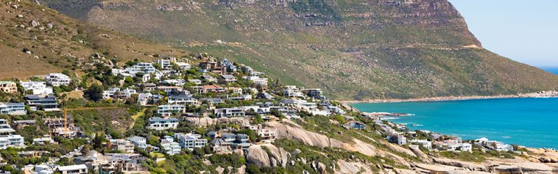 A beautiful shot of buildings on a hill at  turquoise beach in Cape Town, South Africa