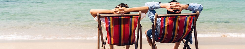 Romantic lovers young couple relaxing sitting together on the tropical beach and looking to the sea.Summer vacations